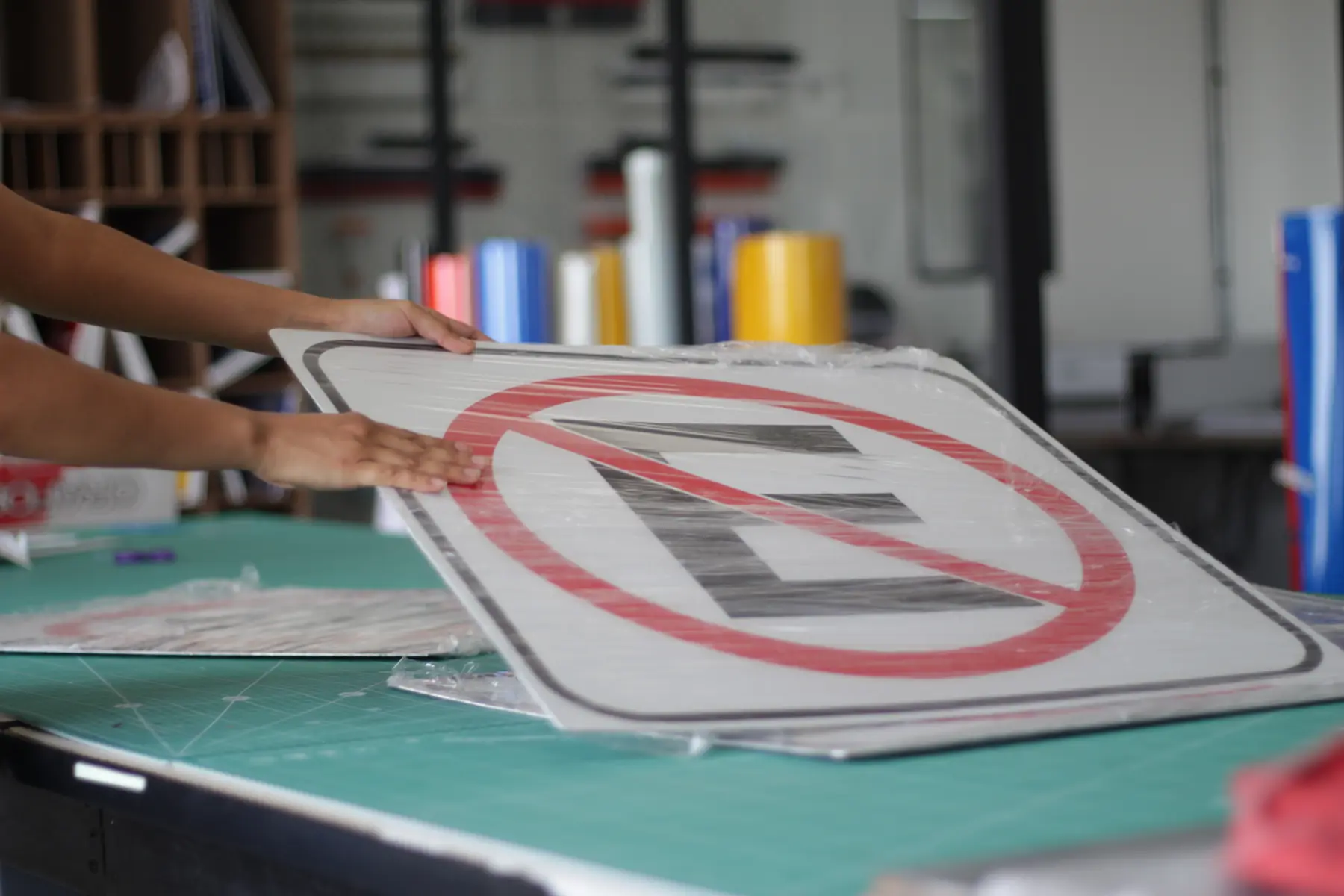Manos montando un señalamiento sobre el tapete de corte en el taller de Nyne Print